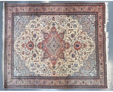 A Persian Tabriz Heriz design hand woven wool floor carpet rug. The carpet having a central pink medallion of geometric flora