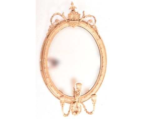 A 19th century George III oval gilt wood and gesso worked girandole mirror. The mirror of rococo influence, the frame of gilt