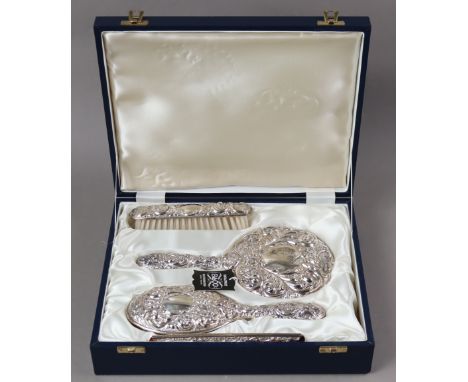 An Elizabeth II silver-mounted dressing table set with embossed mask, flower, &amp; leaf-scroll decoration, comprising a hand