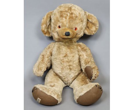 A 1950’s Merrythought large teddy bear with a bell to its left ear, 64cm tall.
