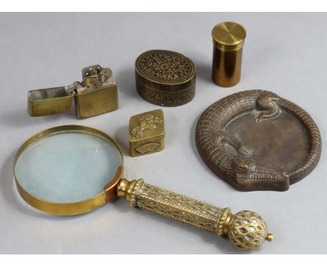A bronzed novelty pin-tray in the form of a crocodile; a brass magnifying glass; a cigarette lighter; a brass lens case; &amp