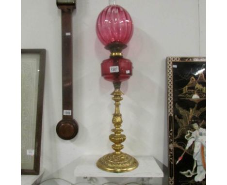 An oil lamp with cranberry glass font and shade