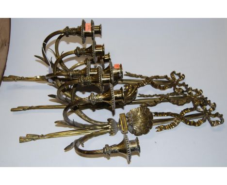 A set of three brass three-sconce wall light fittings, each surmounted by an bow and clam shell, length 57cm