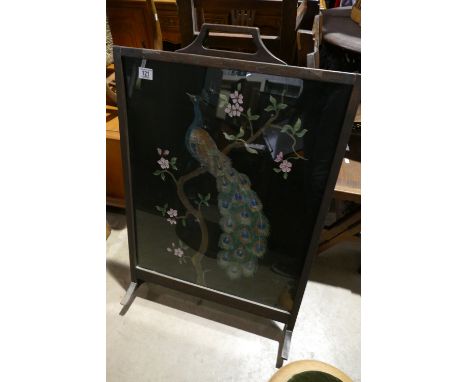 An early 20th century fire screen showing a carved painted peacock on a blossom tree