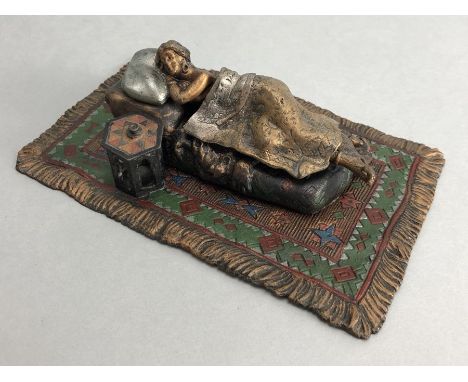 Cold painted bronze of a nude sleeping lady in a bed on a carpet, approx 16cm in length