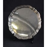 A George V silver salver, of circular form having a Chippendale style rim raised on three scroll
