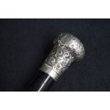 A George V silver mounted walking stick, the repousse pommel having decorative scroll decoration