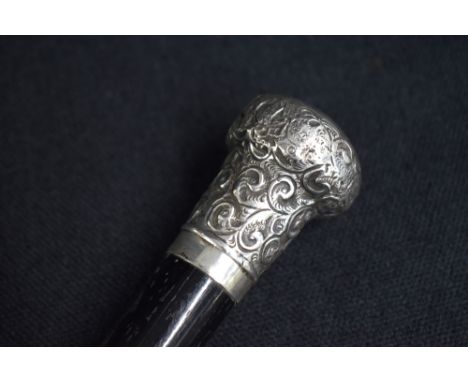 A George V silver mounted walking stick, the repousse pommel having decorative scroll decoration to the ebonised cane, marks 