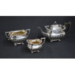 An Edwardian silver three piece tea set, comprising a tea pot, cream and sugar, of rectangular