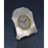 An early 20th century white metal (presumed silver) desk clock, having engine turned decoration to