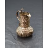 An Eastern white metal cream jug, of bulbous form having a narrow spout opposed by a handle in the