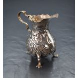 A Georgian silver cream jug, of bulbous form having a Chippendale style rim, shallow spout opposed