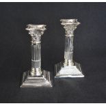 A pair of George V silver Corinthian column candlesticks, having concave square detachable sconces