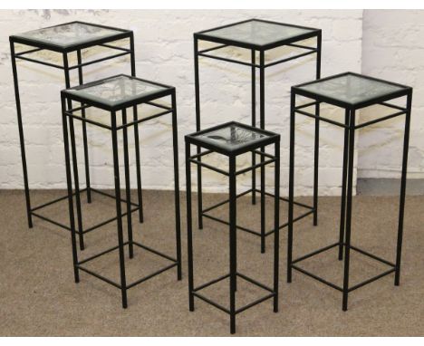 Five graduated metal and glass topped lamp tables.