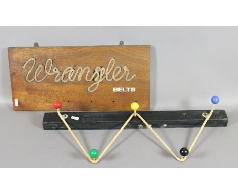 A 1960s wirework coat peg and a Wrangler belts advertising wooden shops plaque.