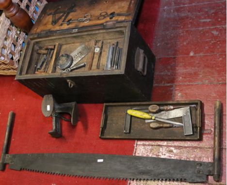 A tool box and contents of old tools along with a two man tree saw and a metal hobbing foot.