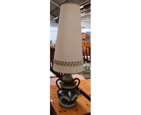 A table lamp with green and brown stoneware base and tapering cream lamp shade, 112cmH