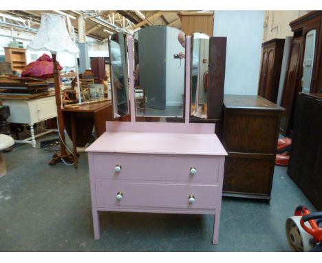 A pink dressing table with folding triple mirror and two drawers with green and white check ceramic handles