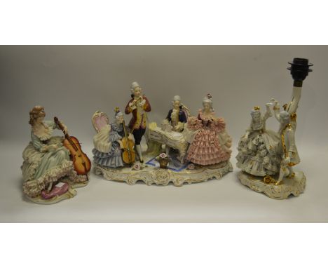 A continental porcelain figural group; another of a Lady playing a cello; a continental figural table lamp (3)