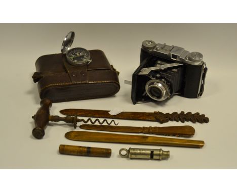 An early 20th century corkscrew;  a German treen letter opener;  The Metropolitan patent whistle;  a compass;  a Balda camera