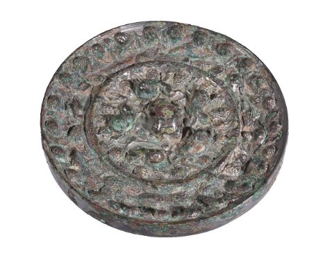 A Chinese bronze mirror, Tang Dynasty, cast with central knop formed by a crouching beast encircled by further beasts amongst