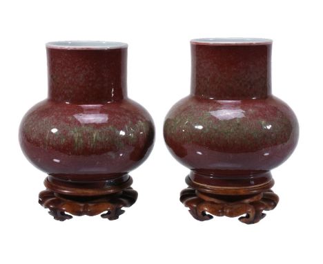 A pair of Chinese peach blossom-glazed bottle vases, formed with a compressed ovoid body supporting a cylindrical neck, the e
