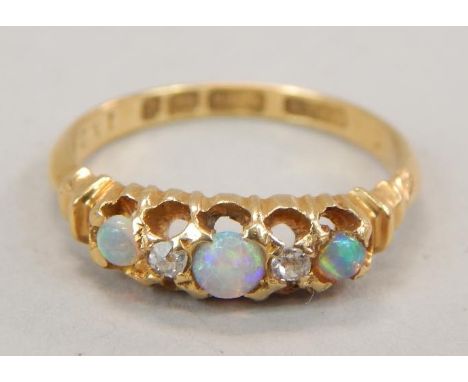 A Victorian opal and diamond dress ring, set with three opals and two tiny diamonds, yellow metal, marked 18ct, 2.7g all in. 