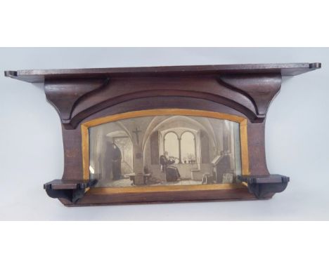 A mahogany stained hardwood Arts and Crafts overmantel, the shelf top held on stylized lotus flower supports, centred by a pr