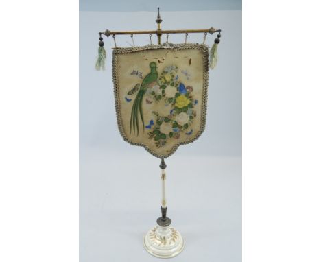 A 19thC face screen, the banner decorated with birds and flowers in an oriental style, on a ceramic column and base, 56cm hig