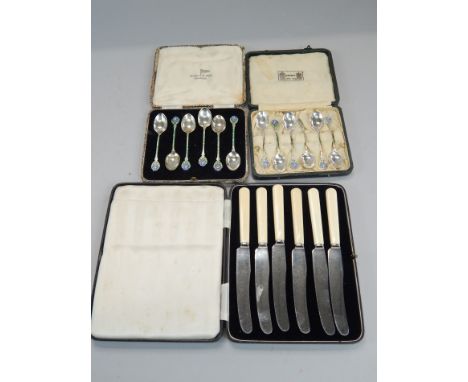 Two sets of six associated silver and enamel coffee spoons, each decorated in Art and Crafts style with a flower, and a set o