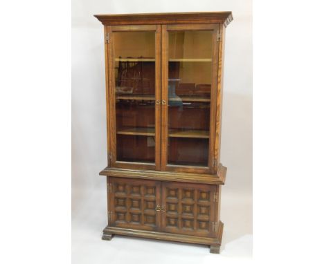 A modern Ercol style oak standing cabinet, with two glazed doors and enclosed base. 