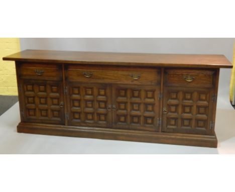 An Ercol type low sideboard, with three frieze drawers above two doors each with nine panels, 101cm wide.