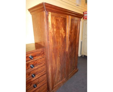 An early Victorian figured mahogany wardrobe, the moulded cornice above two panelled doors, enclosing a shelf and six drawers