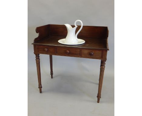 An early Victorian mahogany washstand, the top with a raised back, and a recess for a bowl above two frieze drawers and a fal