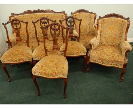 An Edwardian walnut salon suite, with a carved part show frame, padded back, arm rests and seat upholstered in textured velve