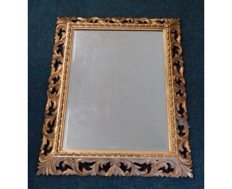 A Continental Florentine wall mirror, with a scroll carved frame and a bevelled mirror plate, 65cm x 80cm