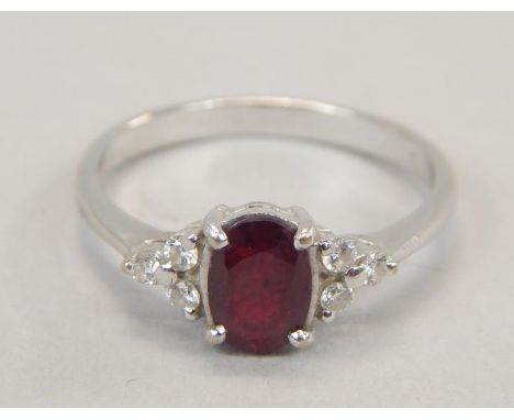 A ruby and diamond dress ring, with central ruby, flanked by three tiny diamonds to each side, white metal, marked 750, 3.1g 