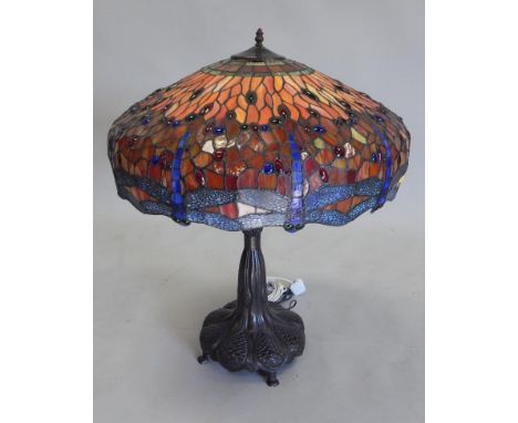 A bronzed Tiffany style lamp, the stained glass shade decorated with dragon flies, the base in Art Nouveau style, decorated w