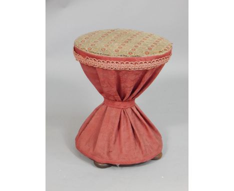 A Victorian hour glass shaped stool, with a woolwork padded seat on bun feet.