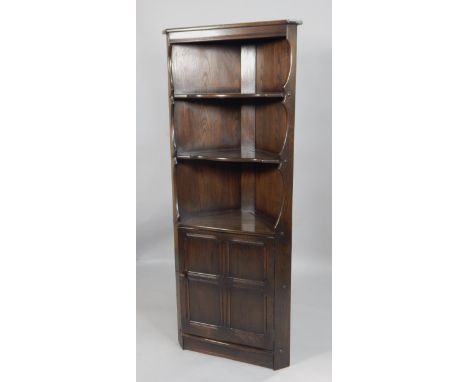 An Ercol stained elm corner cabinet, with two plate shelves above a panelled doors, 74cm wide.