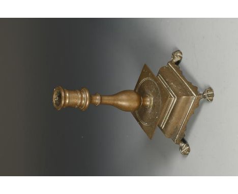 A 17TH CENTURY BRASS CANDLE STICK, the column with bulbous stem on a square dished drip pan and raised moulded base with anim