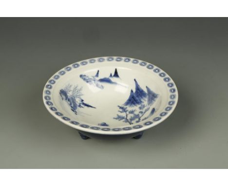 AN UNUSUAL CHINESE BLUE-GLAZED TRIPOD BOWL, the interior decorated in blue and white with a mountain landscape, the base with