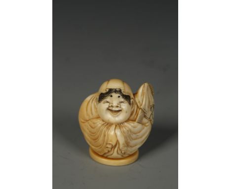 A JAPANESE IVORY SHUNGA NETSUKE, the crouching robed figure with a jovial face, signed to the interior, Meiji, 1.25" high