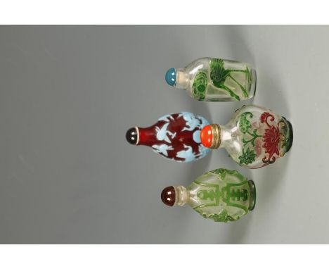 FOUR CHINESE OVERLAID-GLASS SNUFF BOTTLES, one in turquoise showing cranes on a ruby ground; and three others on clear glass;
