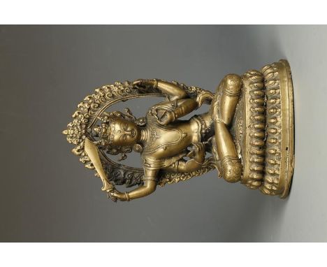 A SINO-TIBETAN BRONZE FOUR-ARMED DEITY holding attributes of a sword, arrow and bow before an ornate back, seated on a lotus 