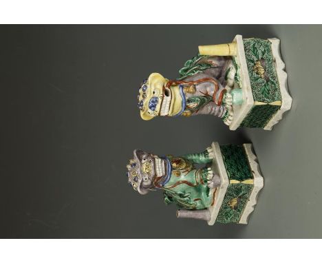 A PAIR OF CHINESE POLYCHROME BUDDHISTIC LION JOSS STICK HOLDERS, each seated on its' hind legs with one paw raised on a ball,