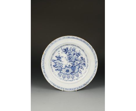 AN 18TH CENTURY DELFT CHARGER painted in blue with a vase of flowers against a trellis and scroll panel enclosed within dot a