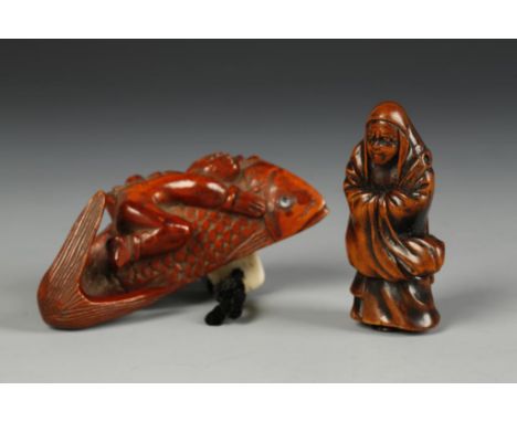 TWO JAPANESE WOOD NETSUKE, the larger example of Ebisu riding a carp, 3.5" long; the other of a standing figure in robes, Mei