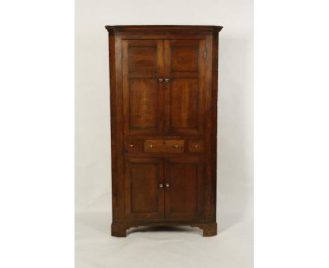 A GEORGE III OAK CORNER CUPBOARD, the upper section with a moulded cornice above twin two-panelled doors and a central small 