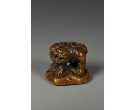 A JAPANESE WOOD SHISHI NETSUKE, the creature standing on all fours with its' head turned to the left, signed, late Edo/Meiji,
